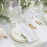 Kolekcja ślubna Zielony Wianek w aranżacji, gdzie stół jest nakryty białym obrusem i delikatnie ozdobiony zielonymi kwiatami
