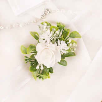 Opaska ze wstążką z białymi kwiatami i zielonymi listkami.