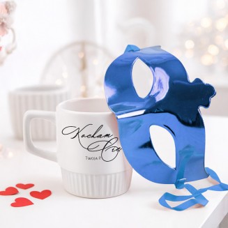 Kubek z napisem „Kocham Cię” i podpisem „Twoja P.” obok niebieskiej maski.