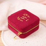 Bordowa szkatułka ze złotym inicjałem.