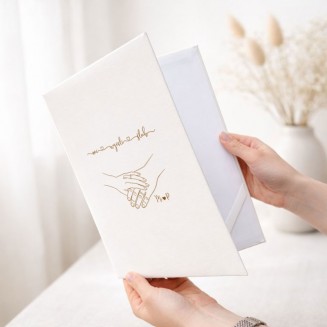 Personalizowana teczka na akt ślubu ma białą okładkę ze złotą grafiką splecionych dłoni oraz inicjałami Pary Młodej.