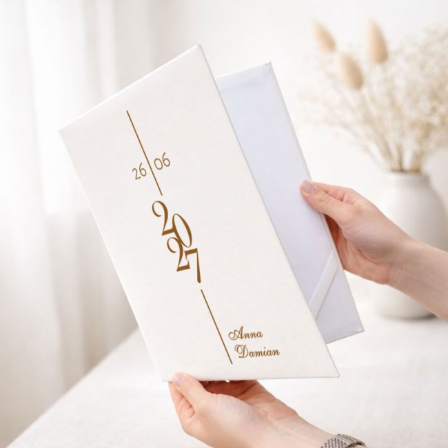 Personalizowana teczka na akt małżeństwa ma elegancką białą okładkę ze złotą datą ślubu oraz imionami