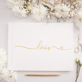 Złoty, metaliczny napis ""love"" na białej okładce księgi gości.