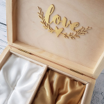 Szkatułka na obrączki ozdobiona jest w środku złotym napisem Love i dekoracyjnym wiankiem z listków
