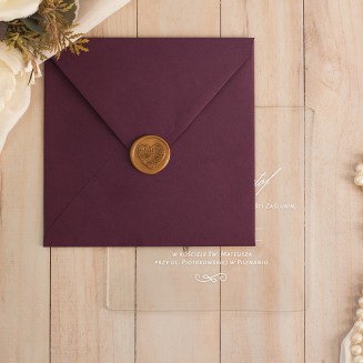 Zaproszenie na szkle akrylowym. Tekst zapisany biała czcionką. Purpurowa koperta zdobiona złotym lakiem z motywem serca.