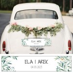 Biała tablica na samochód ślubny, dekorowana delikatnymi zielonymi gałązkami w stylu natural.